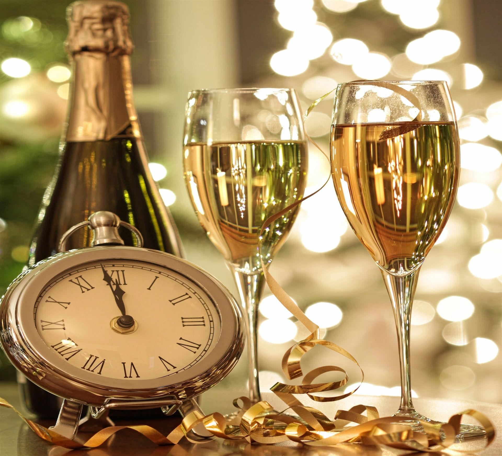 Champagne glasses, gold ribbons, and clock nearing midnight