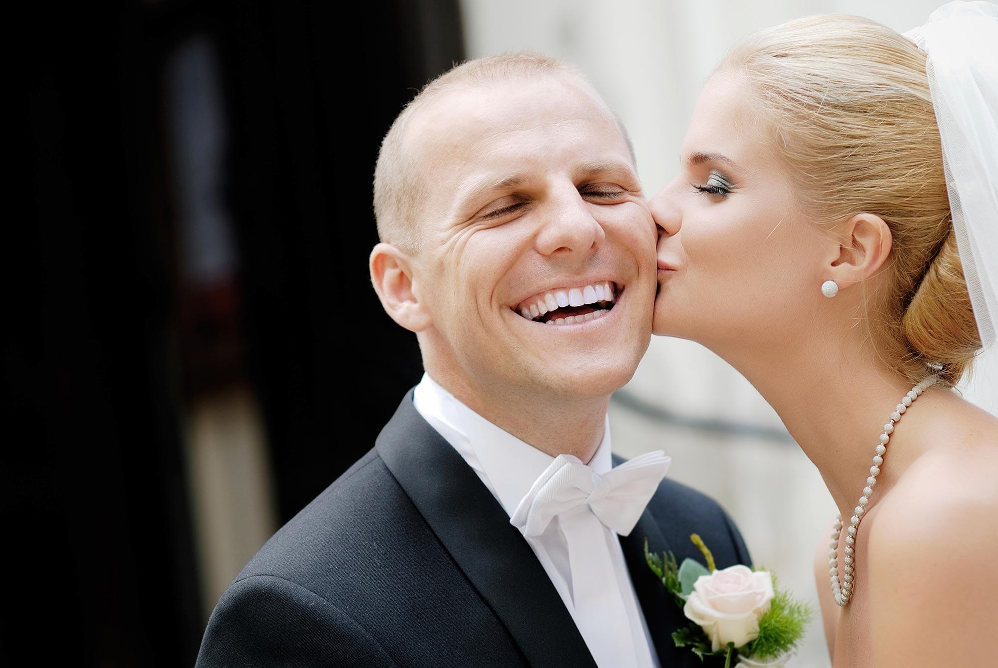 Bride kissing a smiling groom.