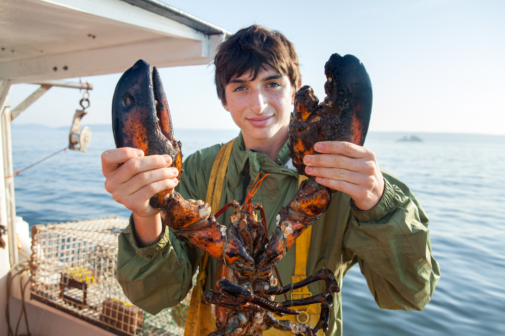 Man holding a large lobster on a boat