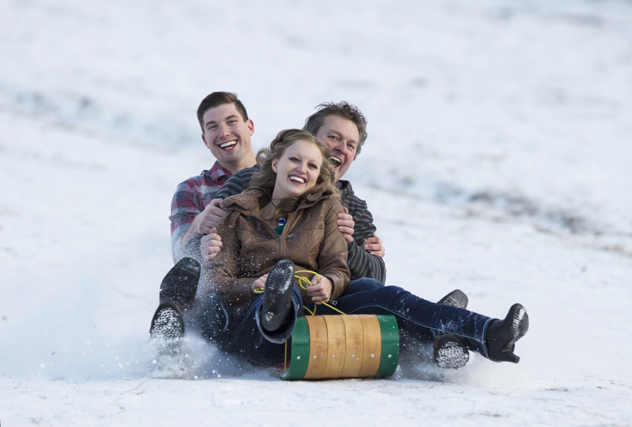 Three people participating in a toboggan race.
